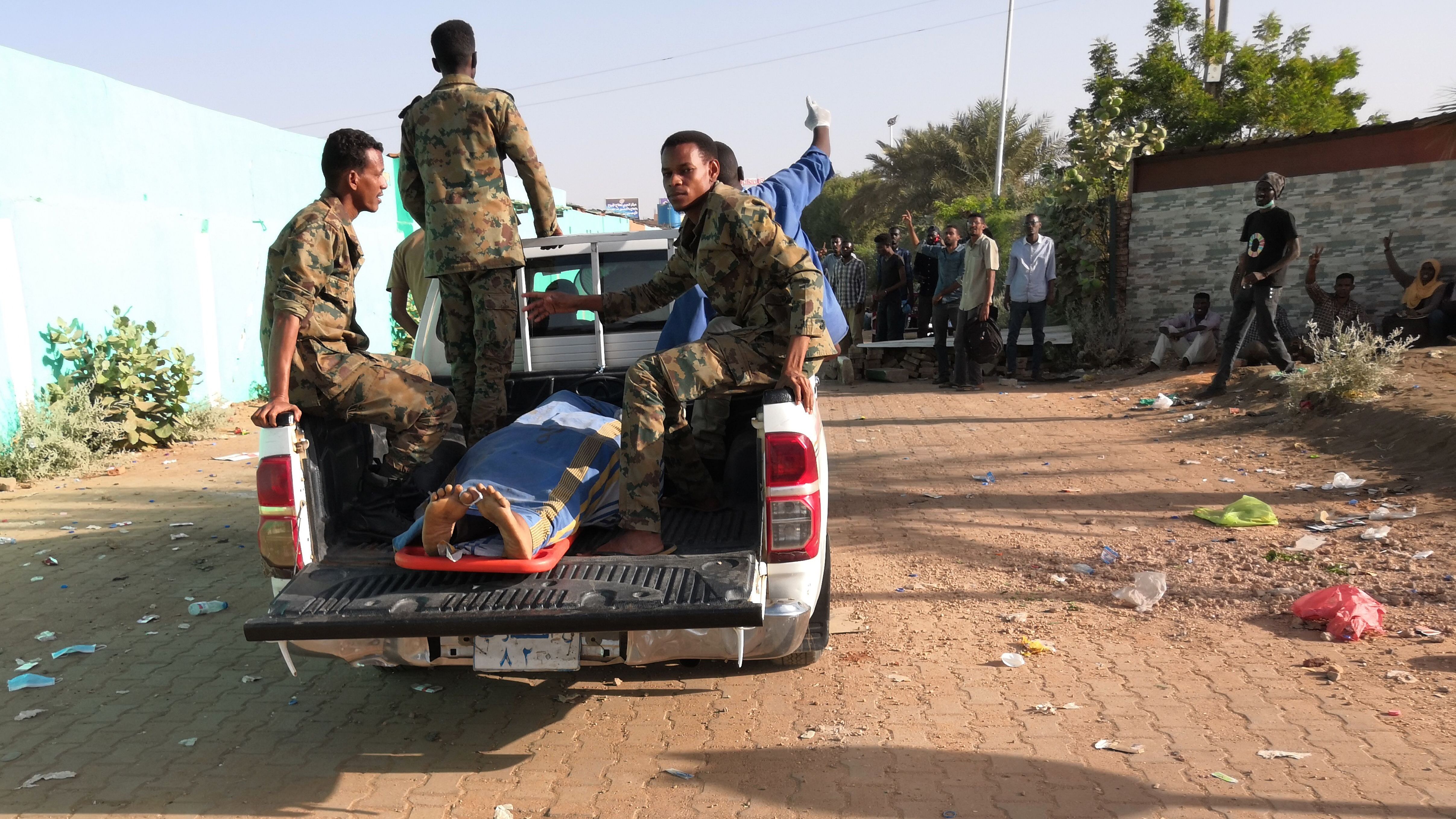 Sudanese soldiers transport a body near the military headquarters on Tuesday, April 9. The Central Committee of Sudan Doctors said 22 people, including five soldiers, had been killed in mass protests.