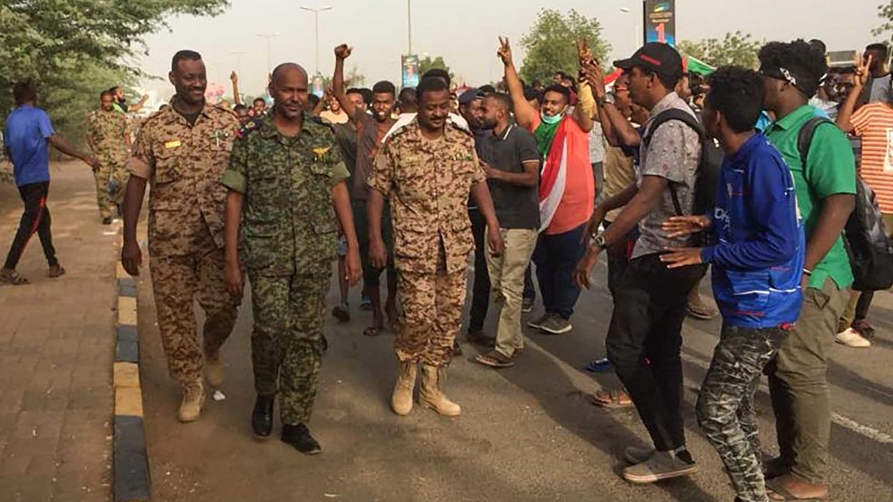 Sudanese protesters cheer Thursday for passing soldiers near military headquarters in Khartoum.