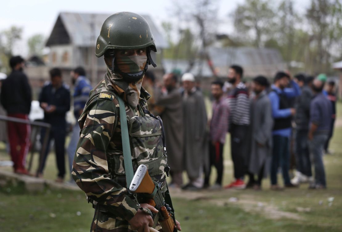 An Indian soldier guards as Kashmiri voters queue up to cast their votes outside a polling station at Shadipora, outskirts of Srinagar, in Indian-controlled Kashmir.