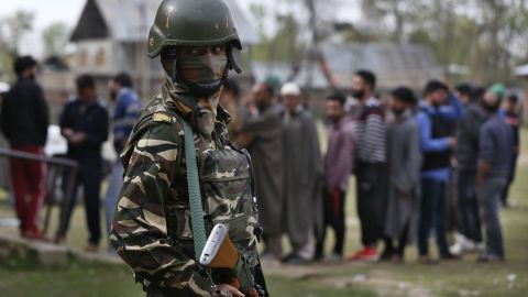 An Indian soldier guards as Kashmiri voters queue up to cast their votes outside a polling station at Shadipora, outskirts of Srinagar, in Indian-controlled Kashmir.