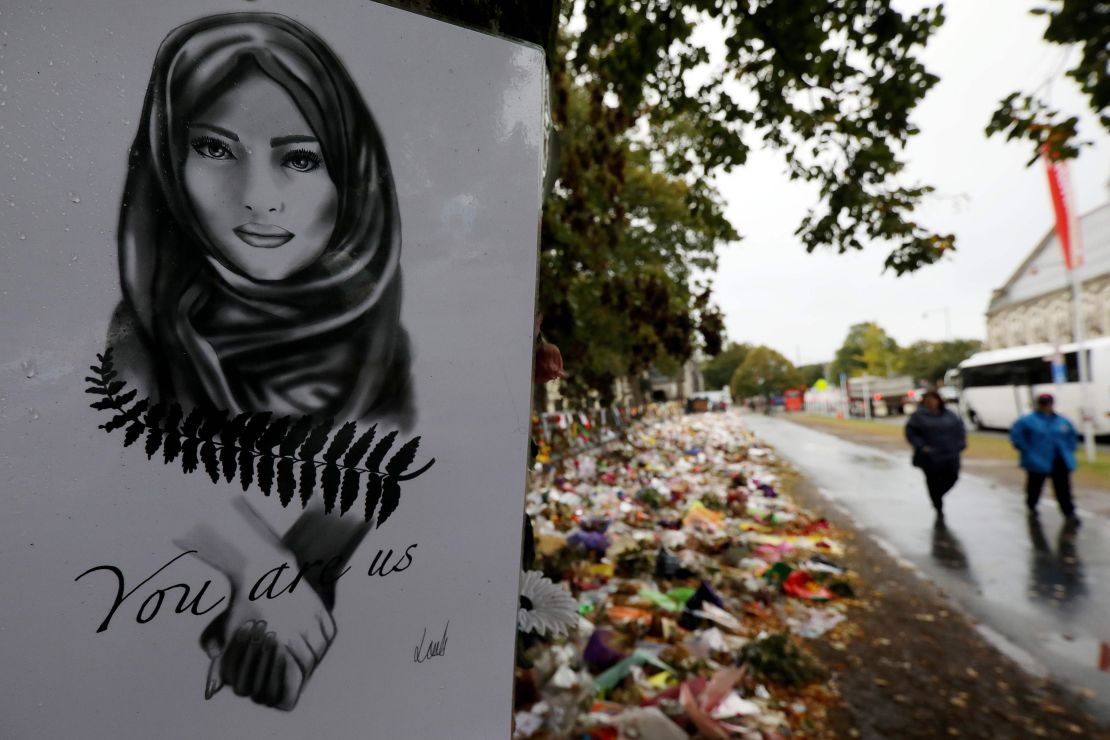 People walk past flowers and tributes displayed in memory of the twin mosque massacre victims outside the Botanical Gardens in Christchurch on April 5, 2019. 