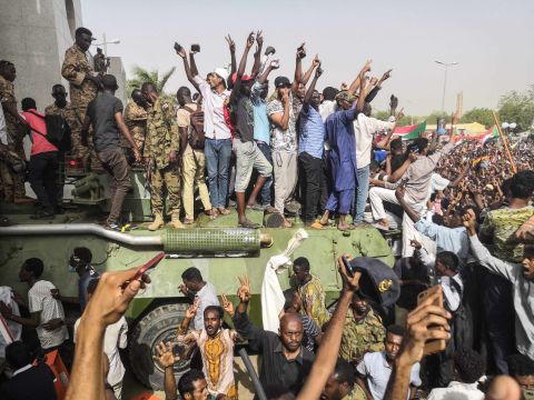 Demonstrators stand on a military vehicle April 11 as they cheer and flash the sign of victory.