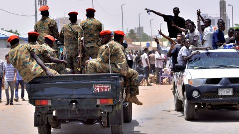 Sudanese demonstrators cheer as they drive towards a military vehicle.