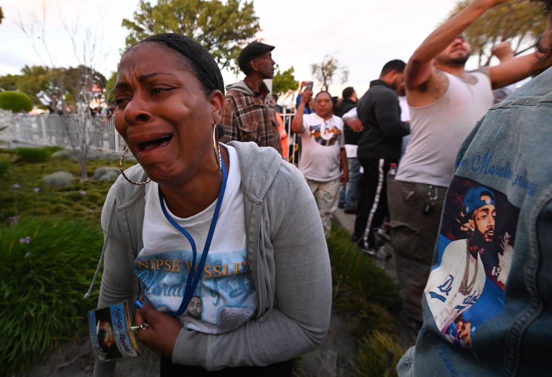 A woman cries as the hearse carrying the remains of rapper  Nipsey Hussle arrives at the funeral home. 