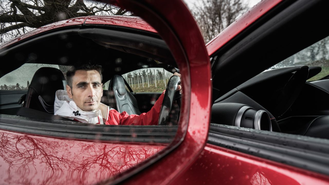 De Simone sits inside a Ferrari Portofino.