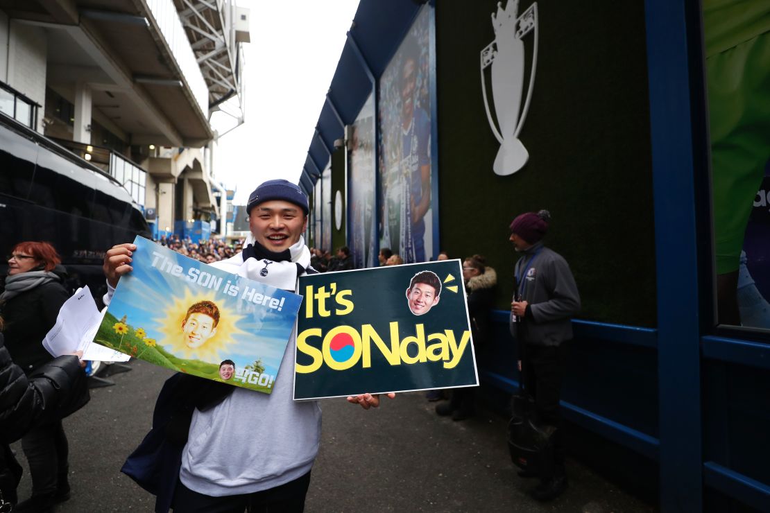 A Tottenham fan poses for a photo with his Son themed posters.