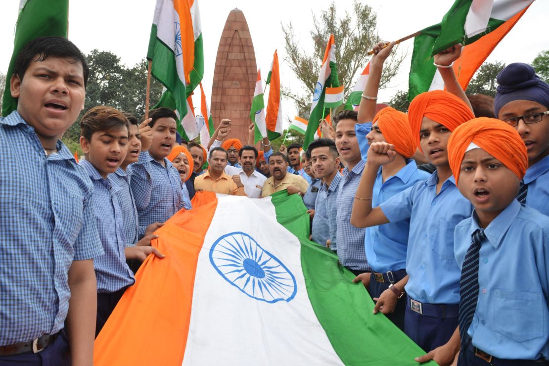 Indian school students hold the national flag in honor of the Jallianwala Bagh massacre, on the eve of the anniversary.