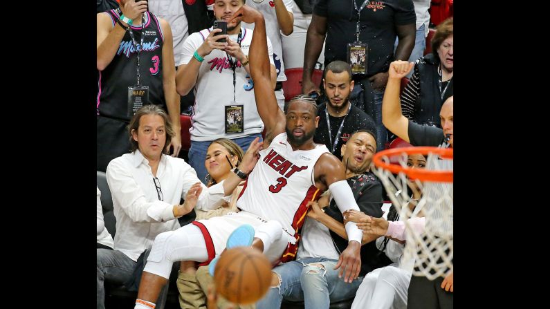 Miami Heat guard Dwyane Wade lands on singer John Legend and Legend's wife, Chrissy Teigen, after Wade missed a basket in the fourth quarter against the Philadelphia 76ers on Tuesday, April 9, in Miami. The next day Wade played his last game before retiring after 16 seasons with the NBA.