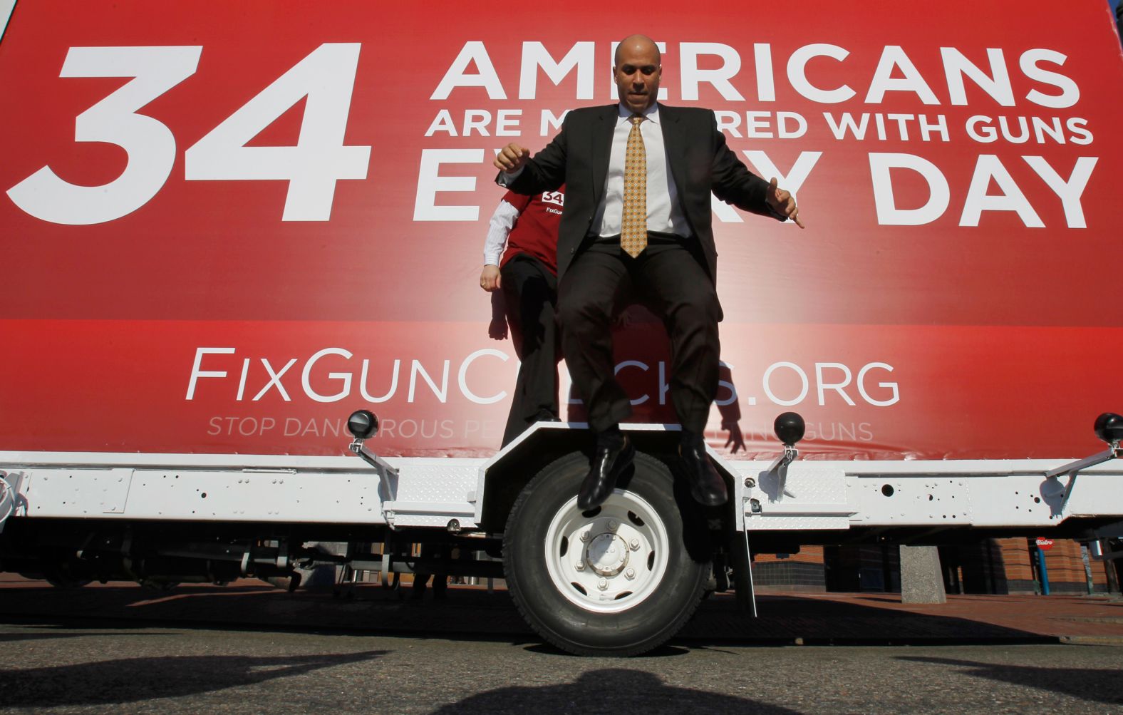 Booker leaps from the wheel cover of a mobile billboard after taking photos on it in February 2011. The truck was driven across the nation to draw attention to US gun laws.