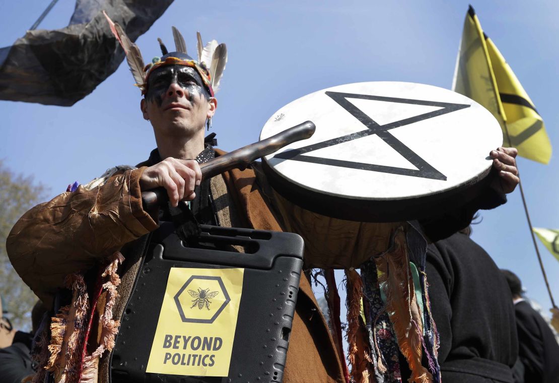 A demonstrator bangs a drum during a climate protest in London's Parliament Square.