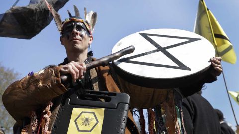 A demonstrator bangs a drum during a climate protest in London's Parliament Square.