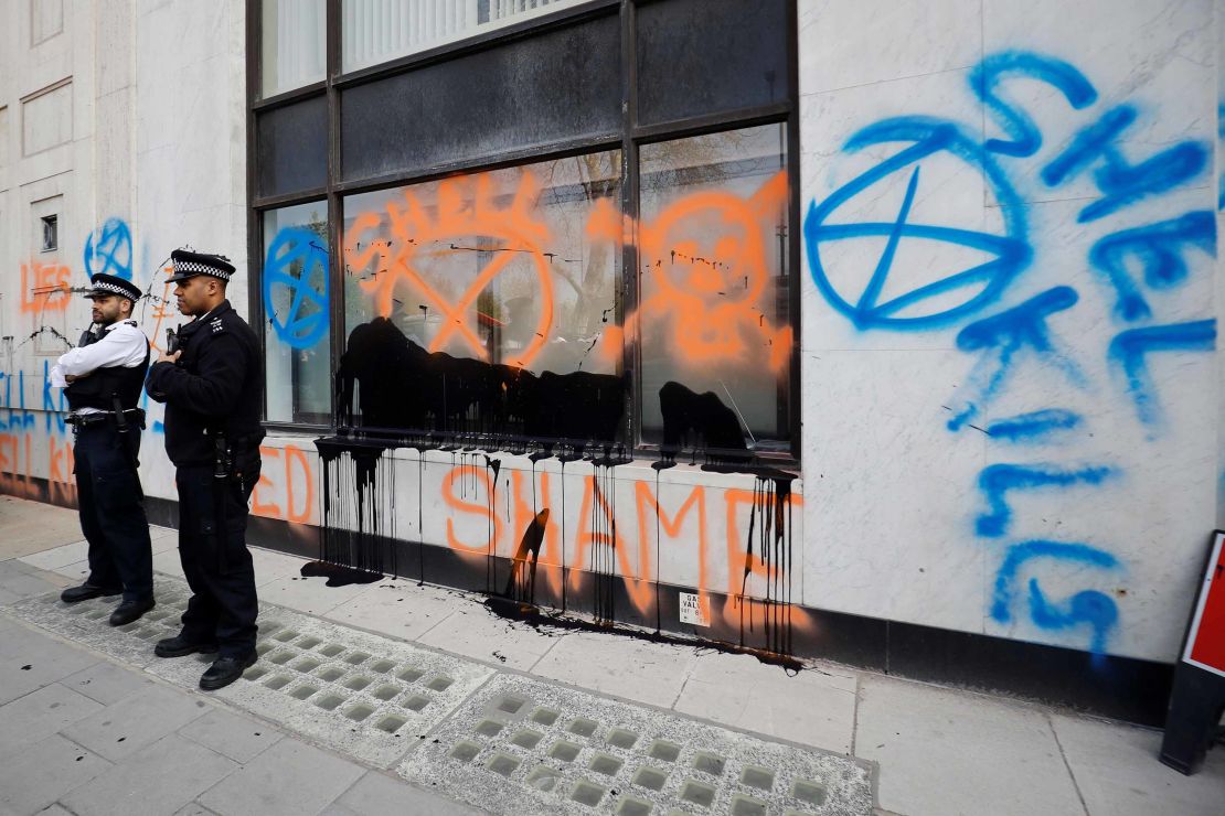 Police officers stand outside the graffiti-covered Shell Centre, the UK offices of Royal Dutch Shell.