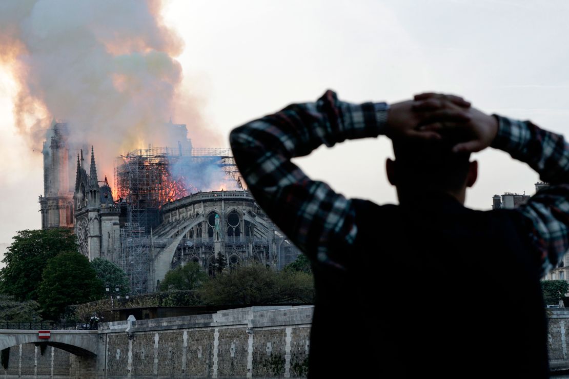 A man watches as the landmark Notre Dame cathedral is engulfed in flames.