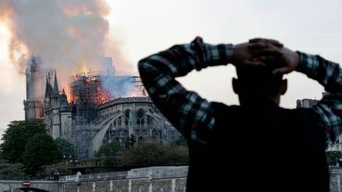 A man watches the landmark Notre-Dame Cathedral burn, engulfed in flames, in central Paris on April 15, 2019.