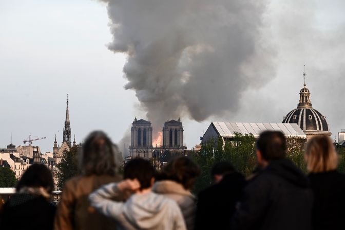 Passers-by watch the cathedral burn. "It's tremendously sad to see this happening to such an iconic monument," bystander Cameron Mitchell <a href="index.php?page=&url=https%3A%2F%2Fwww.cnn.com%2Fworld%2Flive-news%2Fnotre-dame-fire%2Fh_f0e87d76f5c736f2e79dffdf7e363b01" target="_blank">told CNN.</a>