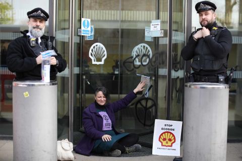 A campaigner sits with her hand glued to the revolving doors at the entrance to the Shell Oil building on April 15.