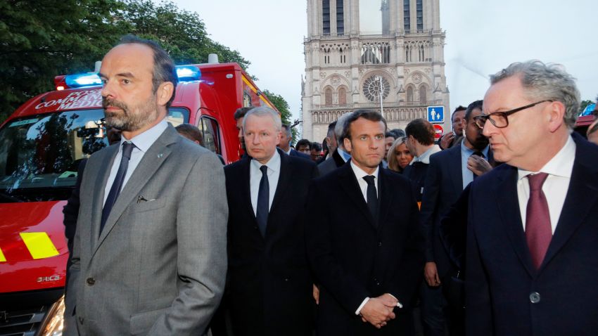 French Prime Minister Edouard Philippe (L), and French President Emmanuel Macron (3rd L) gather in near the entrance of the Notre-Dame de Paris Cathedral in Paris, as flames engulf its roof on April 15, 2019. - A huge fire swept through the roof of the famed Notre-Dame Cathedral in central Paris on April 15, 2019, sending flames and huge clouds of grey smoke billowing into the sky. The flames and smoke plumed from the spire and roof of the gothic cathedral, visited by millions of people a year. A spokesman for the cathedral told AFP that the wooden structure supporting the roof was being gutted by the blaze. (Photo by PHILIPPE WOJAZER / POOL / AFP) (Photo credit should read PHILIPPE WOJAZER/AFP/Getty Images)