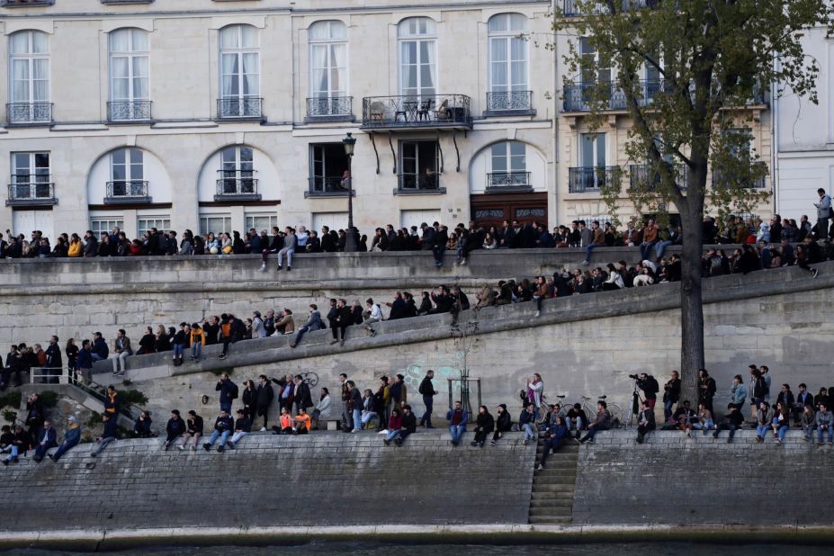 People gather on the banks of the Seine to watch the fire's progress.