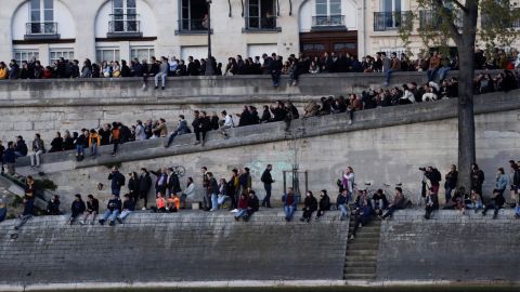People gather on the banks of the Seine to watch the fire's progress.