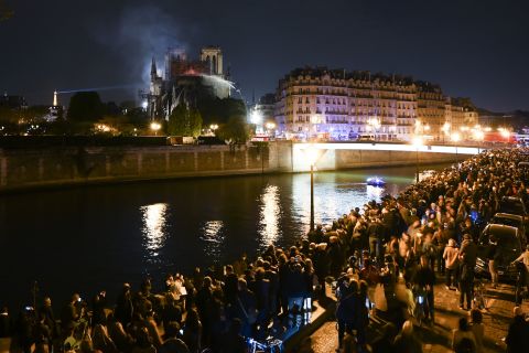 Crowds gathered on the banks of the Seine watch the firefighters' progress.