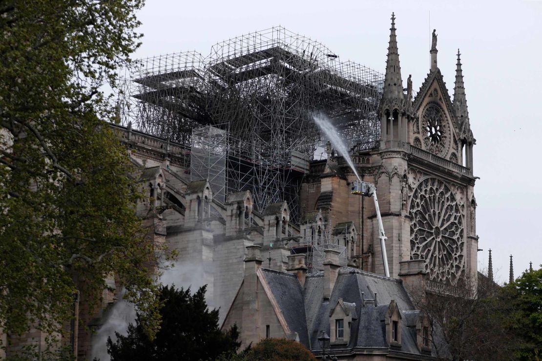 Firefighters spray water as they work to extinguish a fire at Notre Dame Cathedral in Paris early on April 16, 2019.