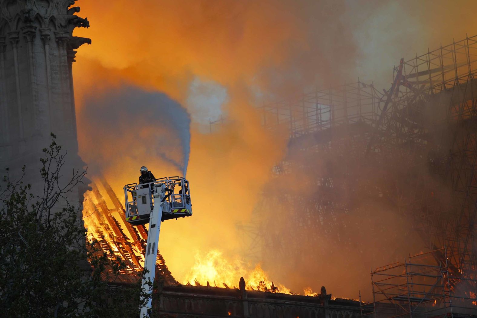 A firefighter uses a hose to tackle the flames as the cathedral's roof burns.