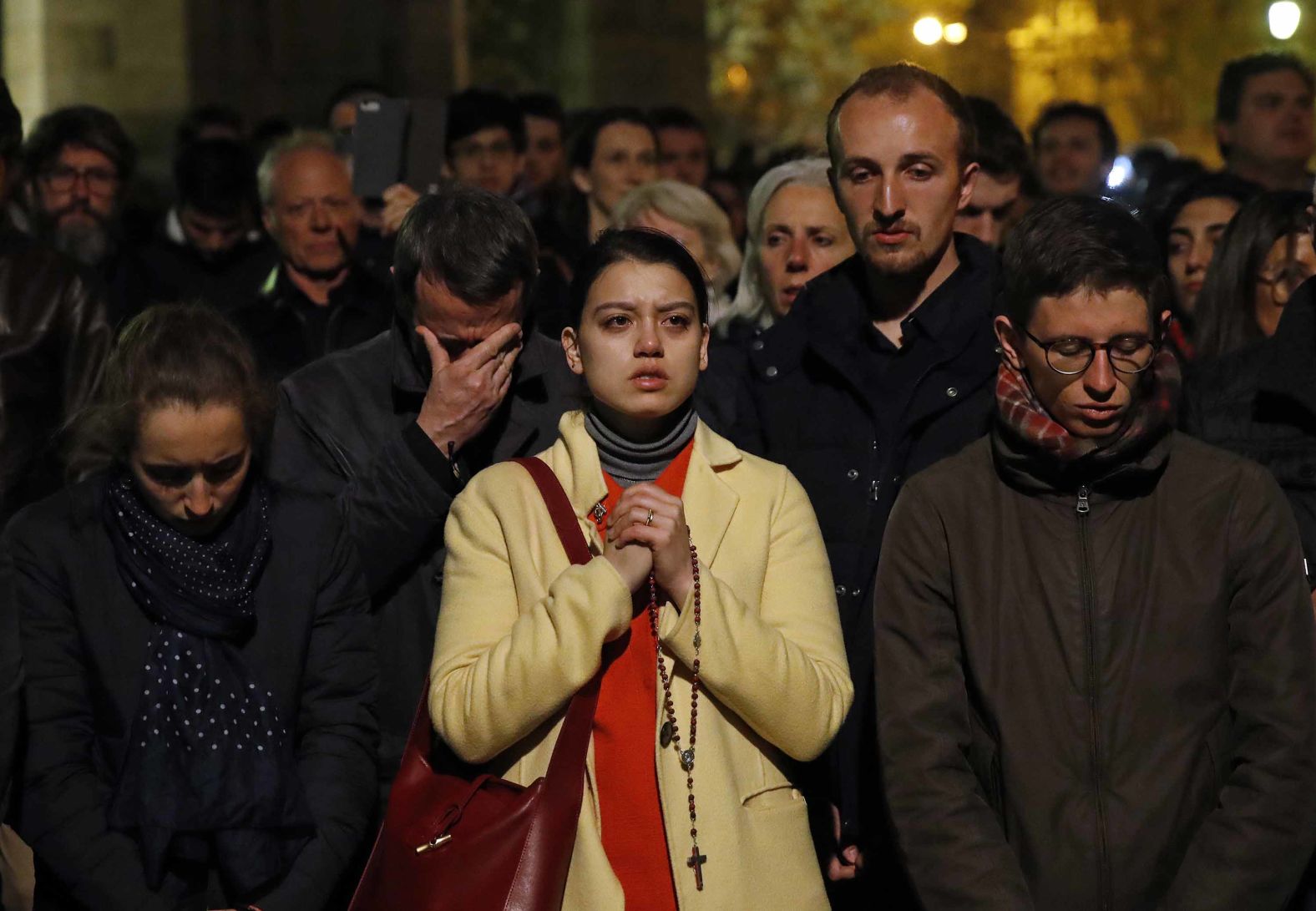 People pray as Notre Dame Cathedral burns on Monday evening.