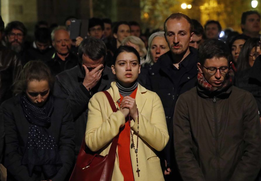 People pray as Notre Dame Cathedral burns on Monday evening.