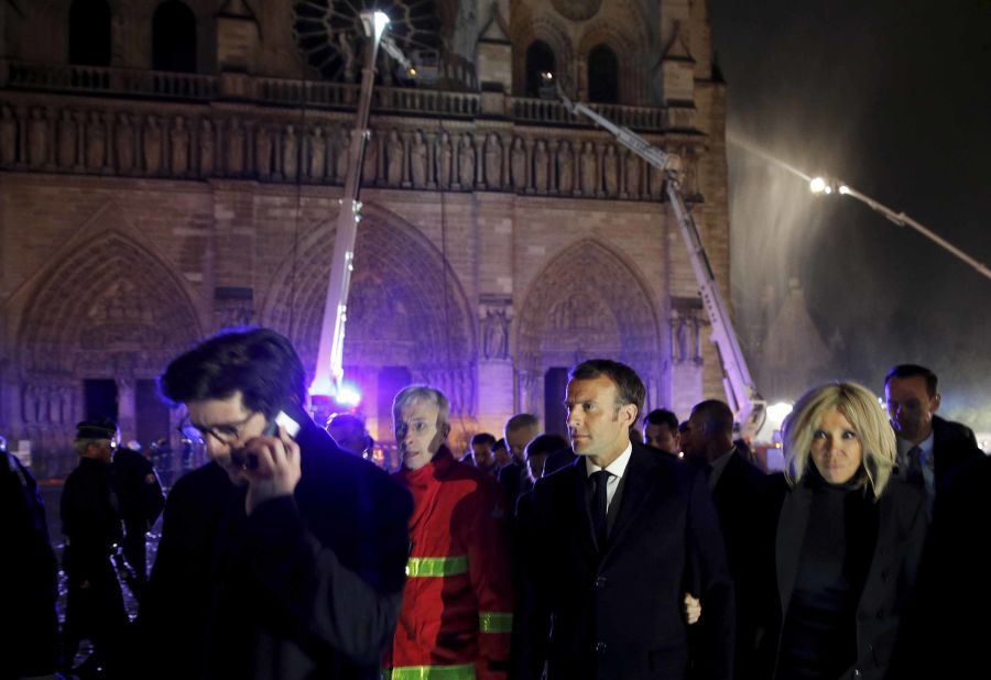 French President Emmanuel Macron, center, and his wife Brigitte at the scene of the fire on Monday evening.