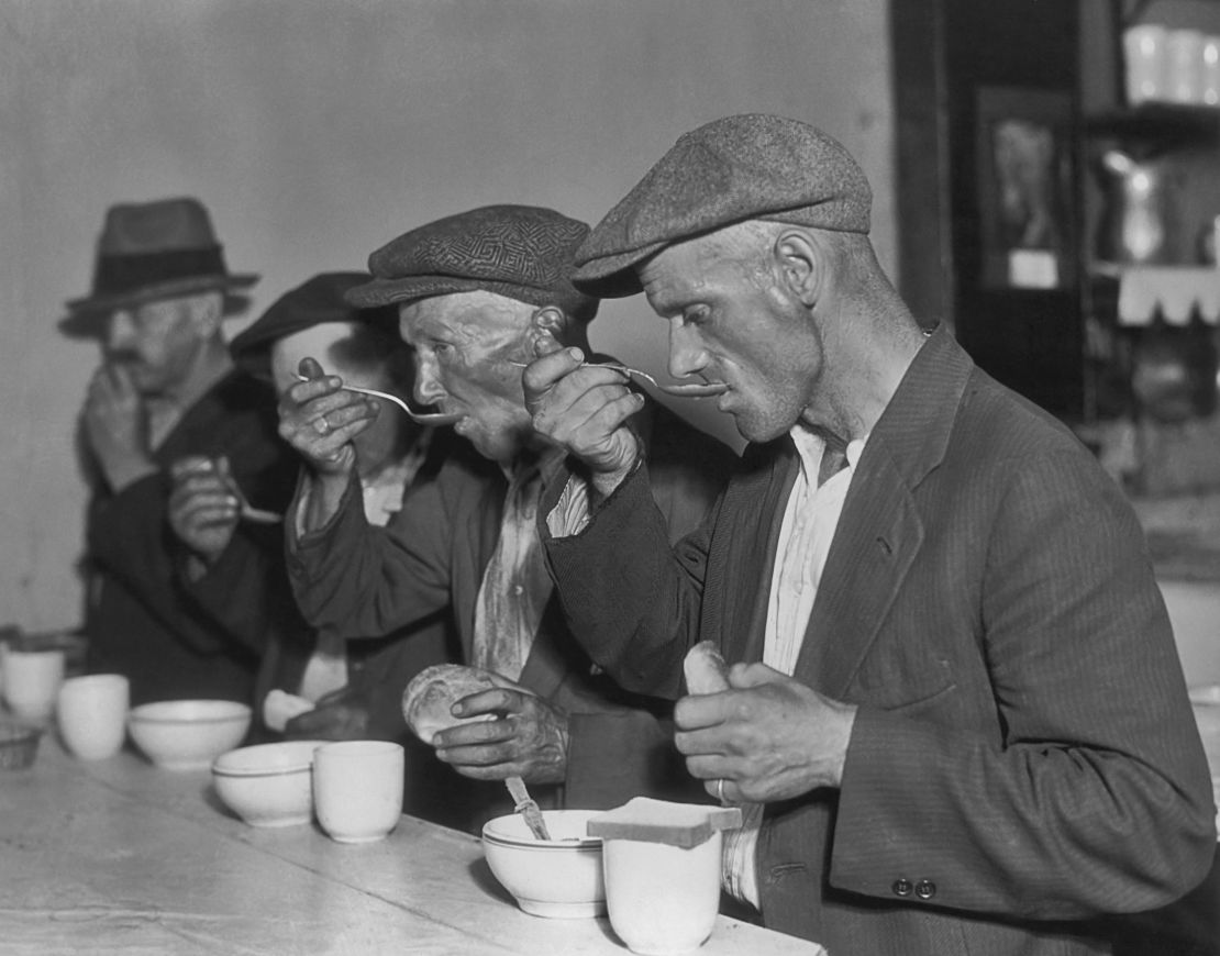 Unemployed men eat soup and bread at a cafeteria circa 1935.
