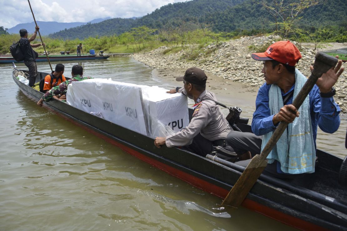 Indonesian election officials transport ballot boxes to a remote village by boat along a river in Manggamat, Southern Aceh province on April 16, 2019.