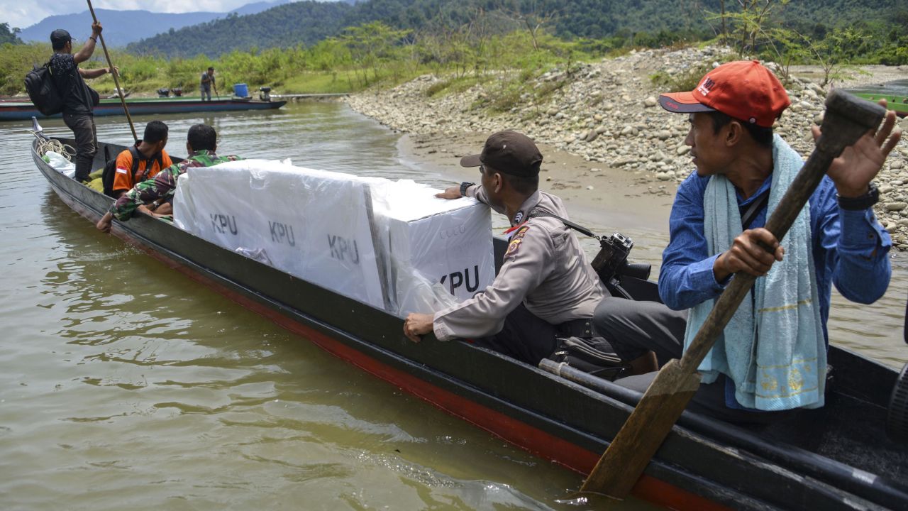 Indonesian election officials transport ballot boxes to a remote village by boat along a river in Manggamat, Southern Aceh province on April 16, 2019.