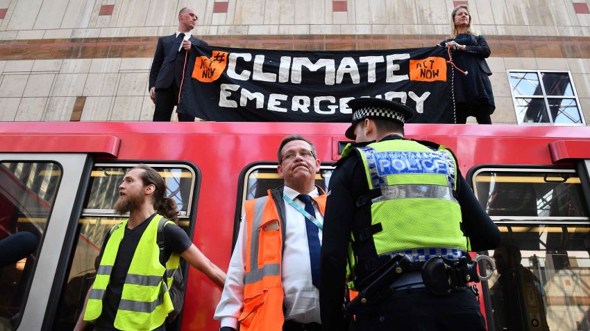 Police stand by as climate change protestors block a DLR train at Canary wharf station on the third day of an environmental protest by the Extinction Rebellion group, in London on April 17, 2019. - Nearly 300 people have been arrested in ongoing climate change protests in London that brought parts of the British capital to a standstill. (Photo by Daniel LEAL-OLIVAS / AFP)        (Photo credit should read DANIEL LEAL-OLIVAS/AFP/Getty Images)