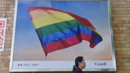 In this photo taken on May 18, 2018 a woman walks past a poster of a rainbow flag outside the Canadian embassy in Beijing. - China's LGBT community may not get much support from authorities, but in a sign of growing tolerance in Chinese society, people are using the power of hashtag campaigns to denounce attacks on gays and lesbians. (Photo by GREG BAKER / AFP)        (Photo credit should read GREG BAKER/AFP/Getty Images)