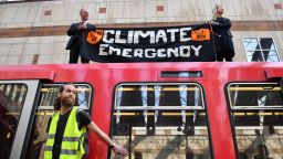 Climate change protestors, one of whom (L) has glued his hand to a window and two others who climbed atop a DLR train at Canary wharf station on the third day of an environmental protest by the Extinction Rebellion group, in London on April 17, 2019. - Nearly 300 people have been arrested in ongoing climate change protests in London that brought parts of the British capital to a standstill, police said Tuesday. (Photo by Daniel LEAL-OLIVAS / AFP)        (Photo credit should read DANIEL LEAL-OLIVAS/AFP/Getty Images)