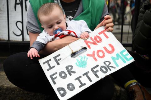 A infant is held alongside a protest sign in Parliament Square, London, on Tuesday.