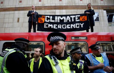 Climate activists hold a sign on top of a Dockland Light Railway train at Canary Wharf station, in east London, as part of ongoing climate change protests in the English capital.