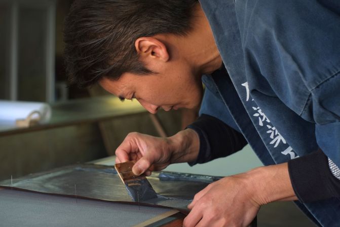 Yuichi Hirose dyes white fabrics with meticulously hand-cut stencils for a kimono, at his family's century-old workshop in Tokyo. 