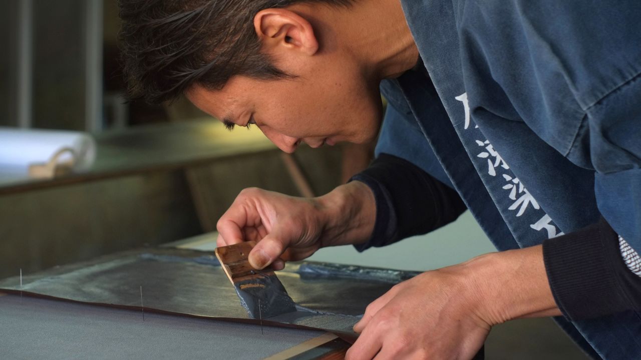 This picture taken on March 1, 2018 shows Yuichi Hirose, a craftsman who dyes white fabrics with meticulously hand-cut stencils for a kimono, working at a century-old workshop in Tokyo. - Once a standard of the Japanese wardrobe, the kimono is now often a garment reserved for special occasions, such as weddings and coming-of-age ceremonies, and is mostly worn by women. (Photo by Kazuhiro NOGI / AFP)        (Photo credit should read KAZUHIRO NOGI/AFP/Getty Images)