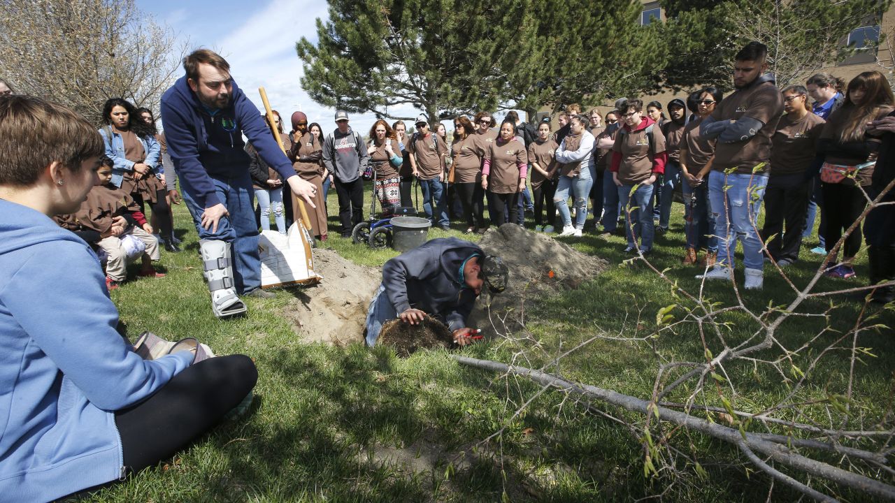 Alex Job, center left, and his brother, Arthur, demonstrate tree planting techniques for a group of about 60 Columbia Basin College students, faculty and staff members during their annual Arbor Day tree planting event in Pasco, Washington, on April 11, 2019. 