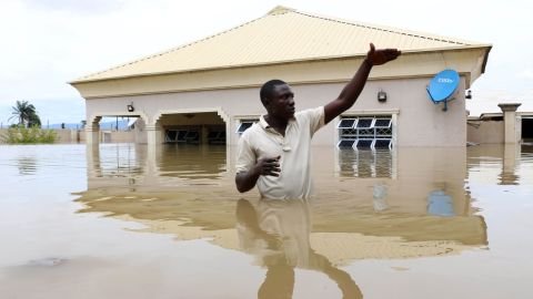 A man gestures next to his flooded house near the Nigerian town of Lokoja in September 2018. Climate change has hurt the economies of warm countries like Nigeria, a new study finds.