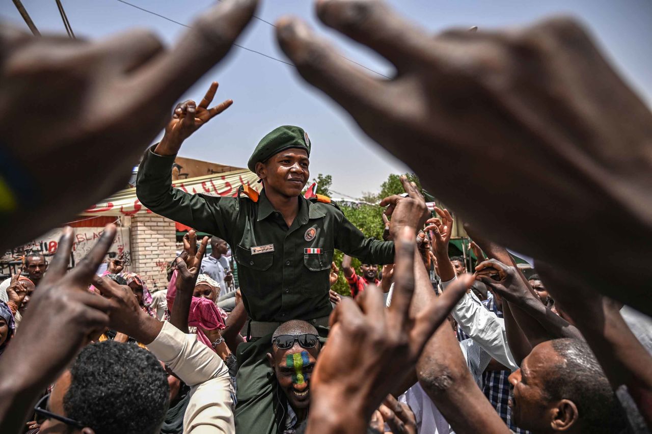 Protesters shout slogans as they carry a soldier flashing the victory sign outside the army headquarters on April 18.