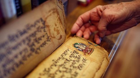 Taylor carefully shows the Tibetan prayer book she keeps in her library.