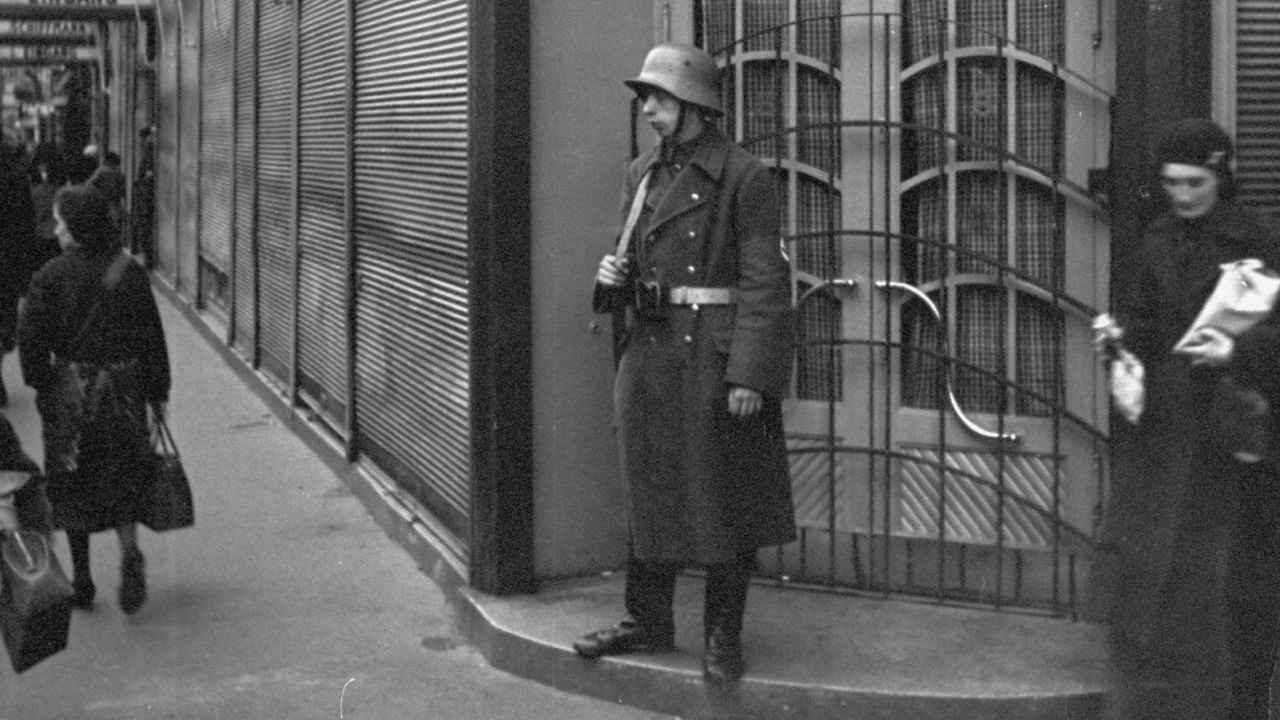 A guard stands outside Schiffmann's department store, a Jewish business, after it was taken over by the Nazis.