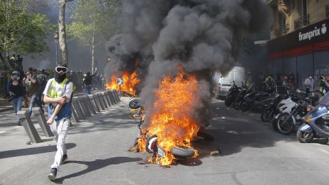 A man runs by a burning motorbike during a yellow vest demonstration in Paris on April 20, 2019.