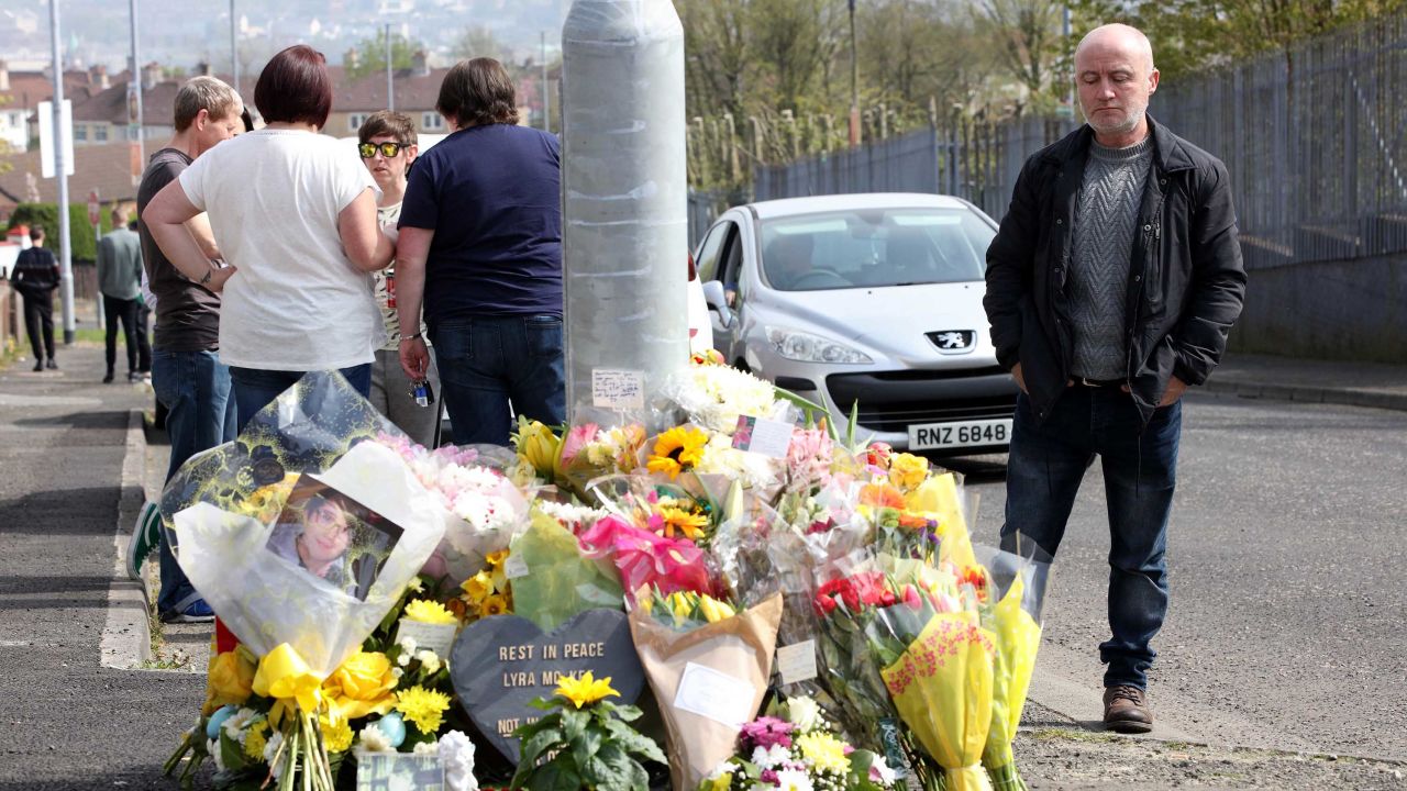 People gather around floral tributes placed at the scene in the Creggan area of Londonderry/Derry in Northern Ireland on April 20, 2019 where journalist Lyra McKee was fatally shot amid rioting.