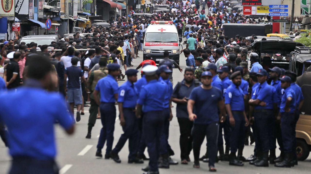 Sri Lankan police officers clear the road as an ambulance drives through carrying injured from bomb blasts in Colombo.