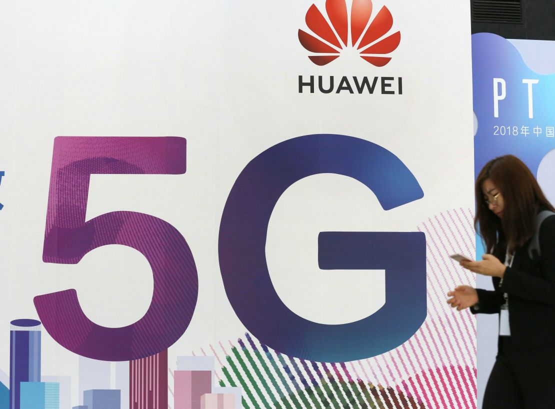 A woman walks past the stand of Huawei featuring 5G technology during the PT Expo China at Beijing National Convention Center.