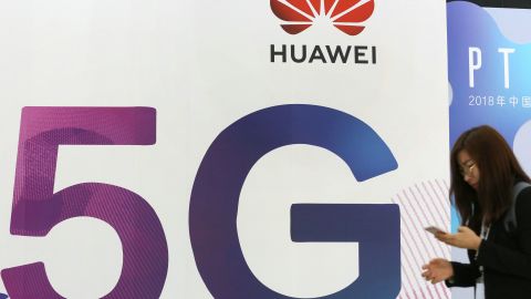 A woman walks past the stand of Huawei featuring 5G technology during the PT Expo China at Beijing National Convention Center.