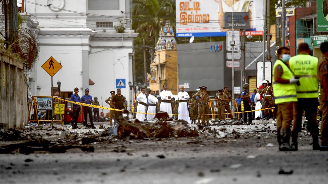 Sri Lankan priests look at the debris of a car after it explodes when police tried to defuse a bomb near St. Anthony's Shrine a day after the Easter Sunday  attacks.